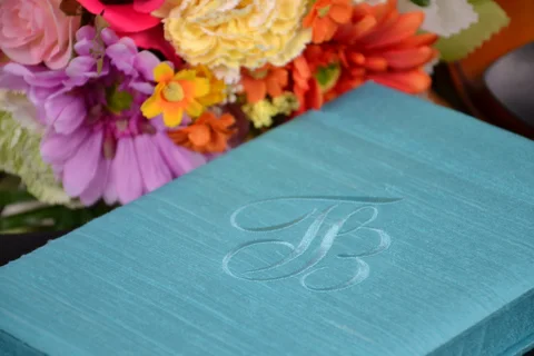 Aqua invitation box with an embroidered initial and flowers