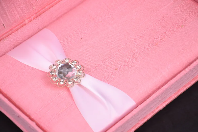 Close view of pink fabric, pale ribbon and a floral jeweled embellishment