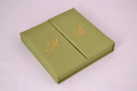 Green gatefold invitation box with gold-toned embroidered initials