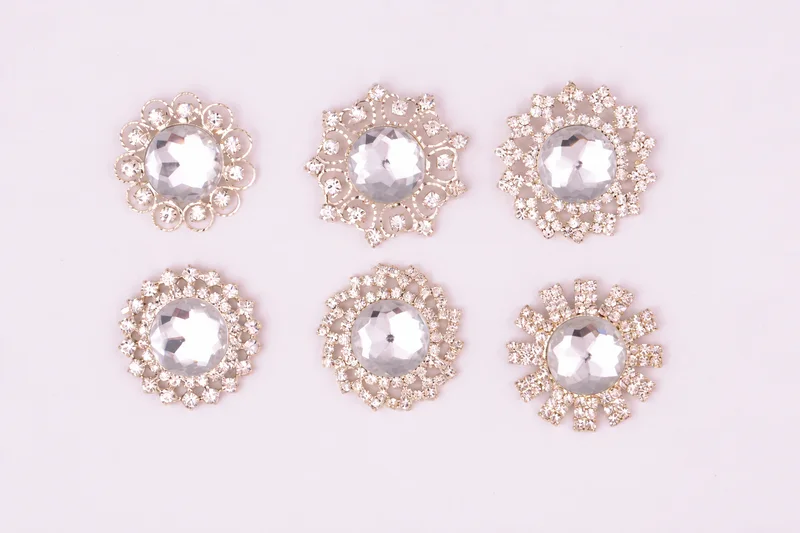 A selection of six circular and floral jeweled invitation embellishments