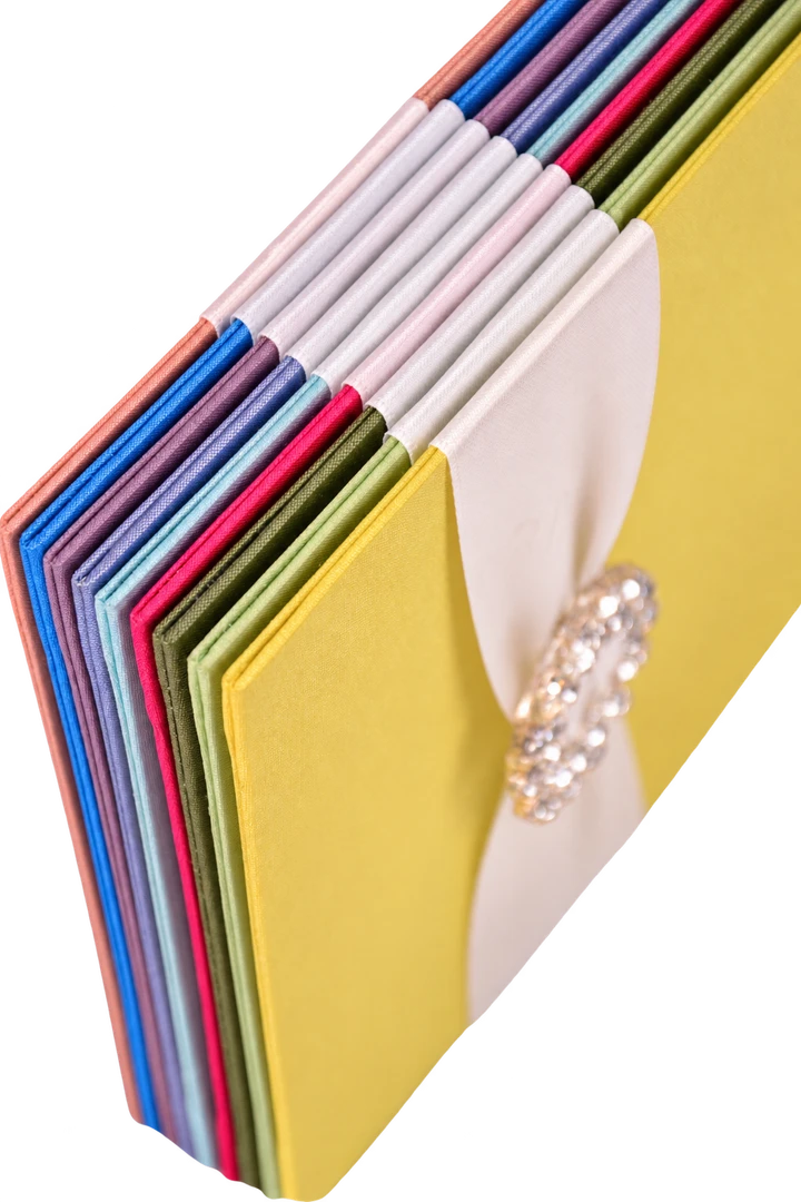 Colourful invitation folios with white ribbon and a crystal ornament, from the Thai Silk Box collection