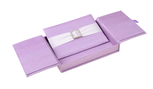 Violet silk gatefold invitation box with two opposing flaps, white ribbon and square jeweled accent