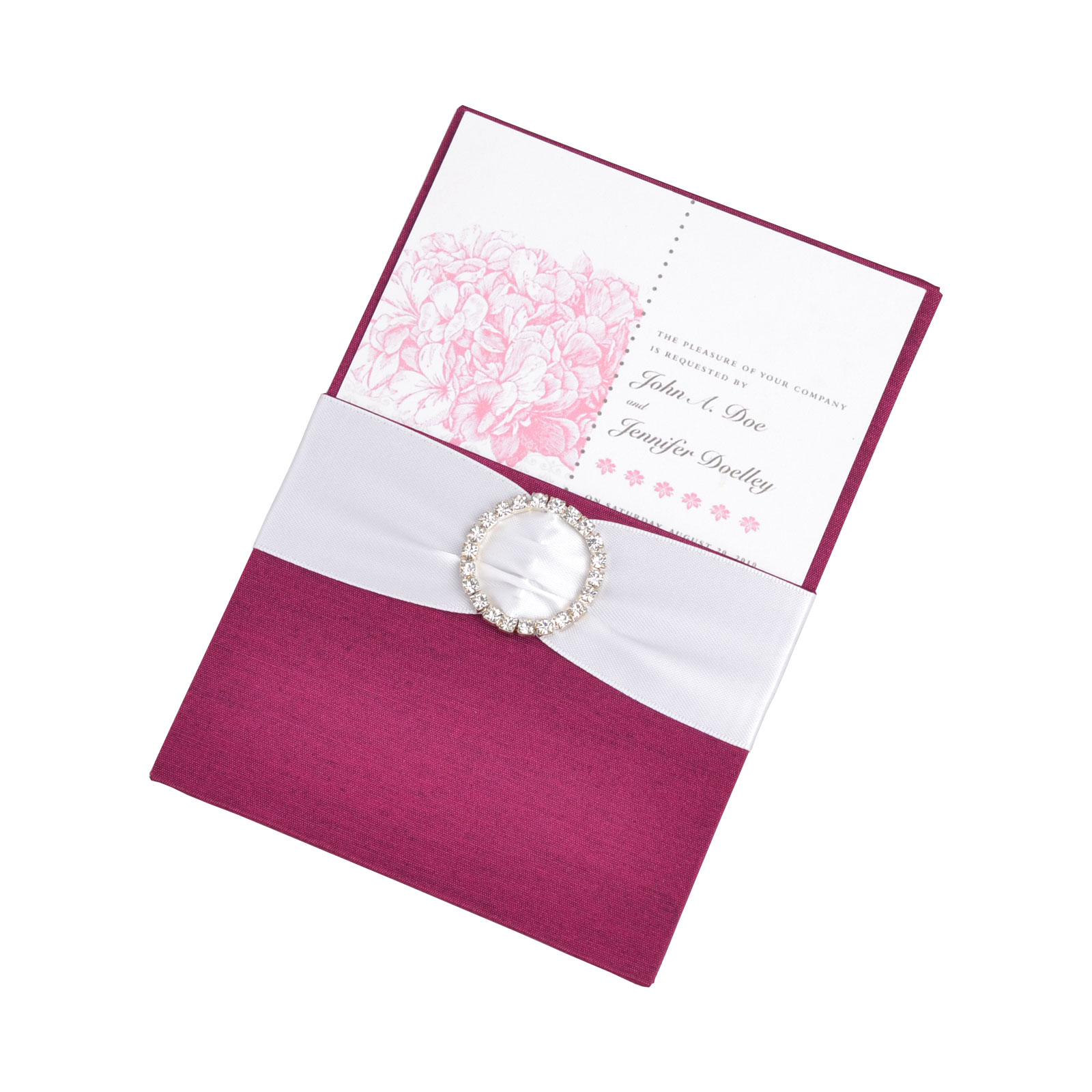 Deep pink silk pocket folio holding a floral invitation, finished with a white ribbon and round jeweled buckle