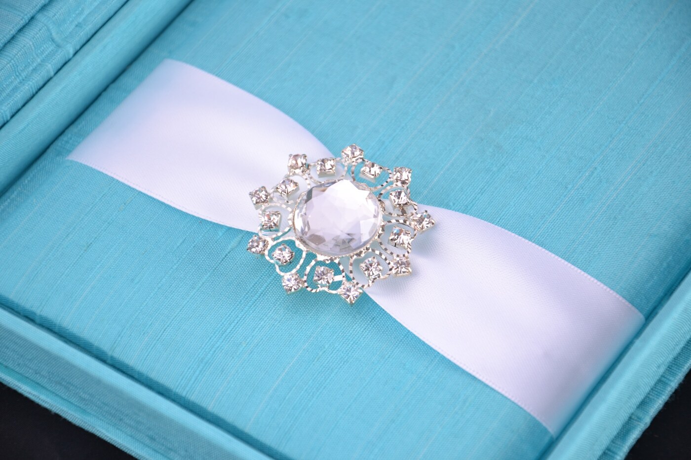 Aqua silk wedding invitation box with white ribbon and crystal jewel embellishment