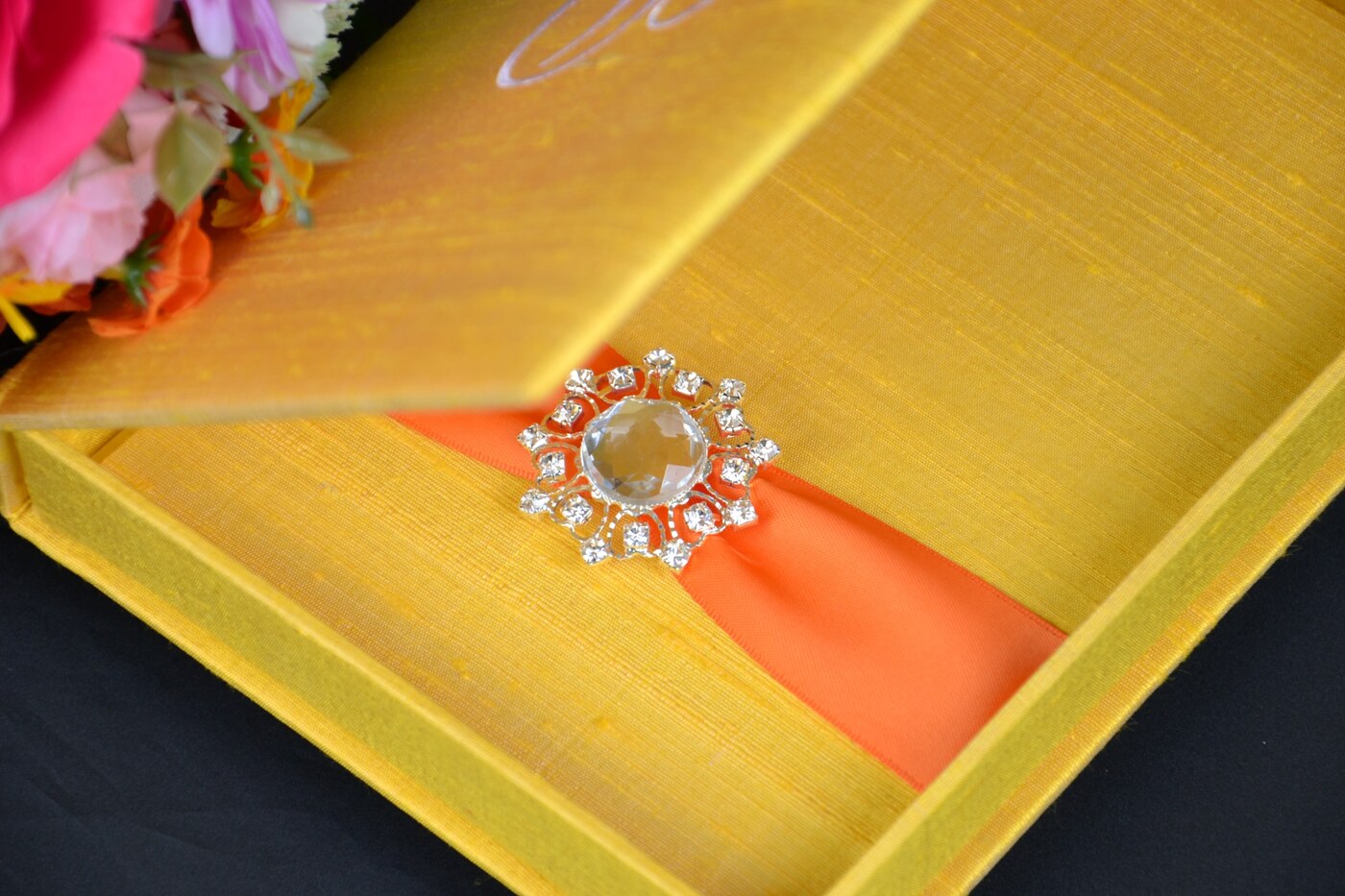 Golden yellow silk wedding invitation box with orange ribbon and crystal jewel embellishment
