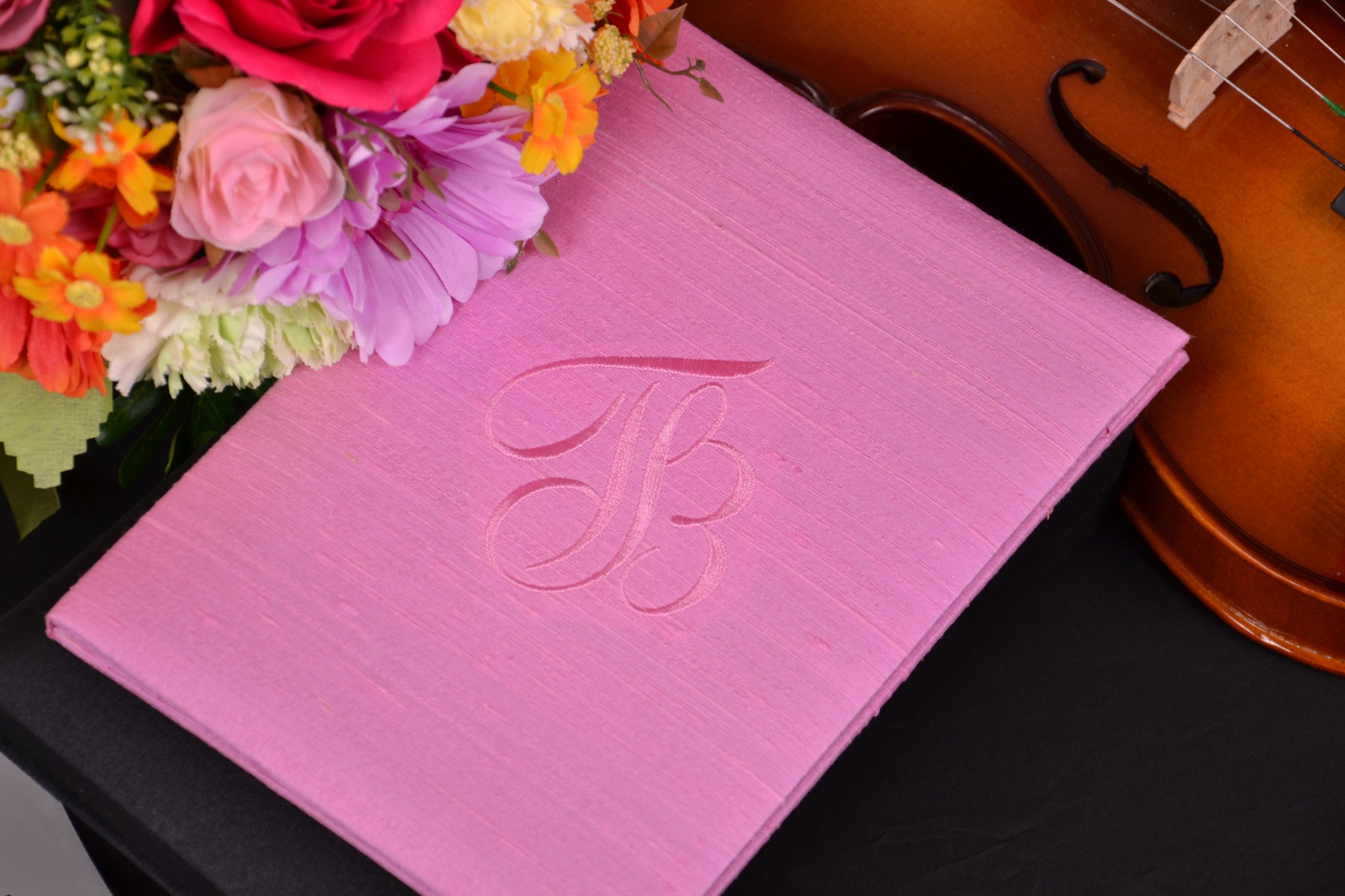 Pink handmade silk wedding invitation folio with embroidered monogram, flowers and violin